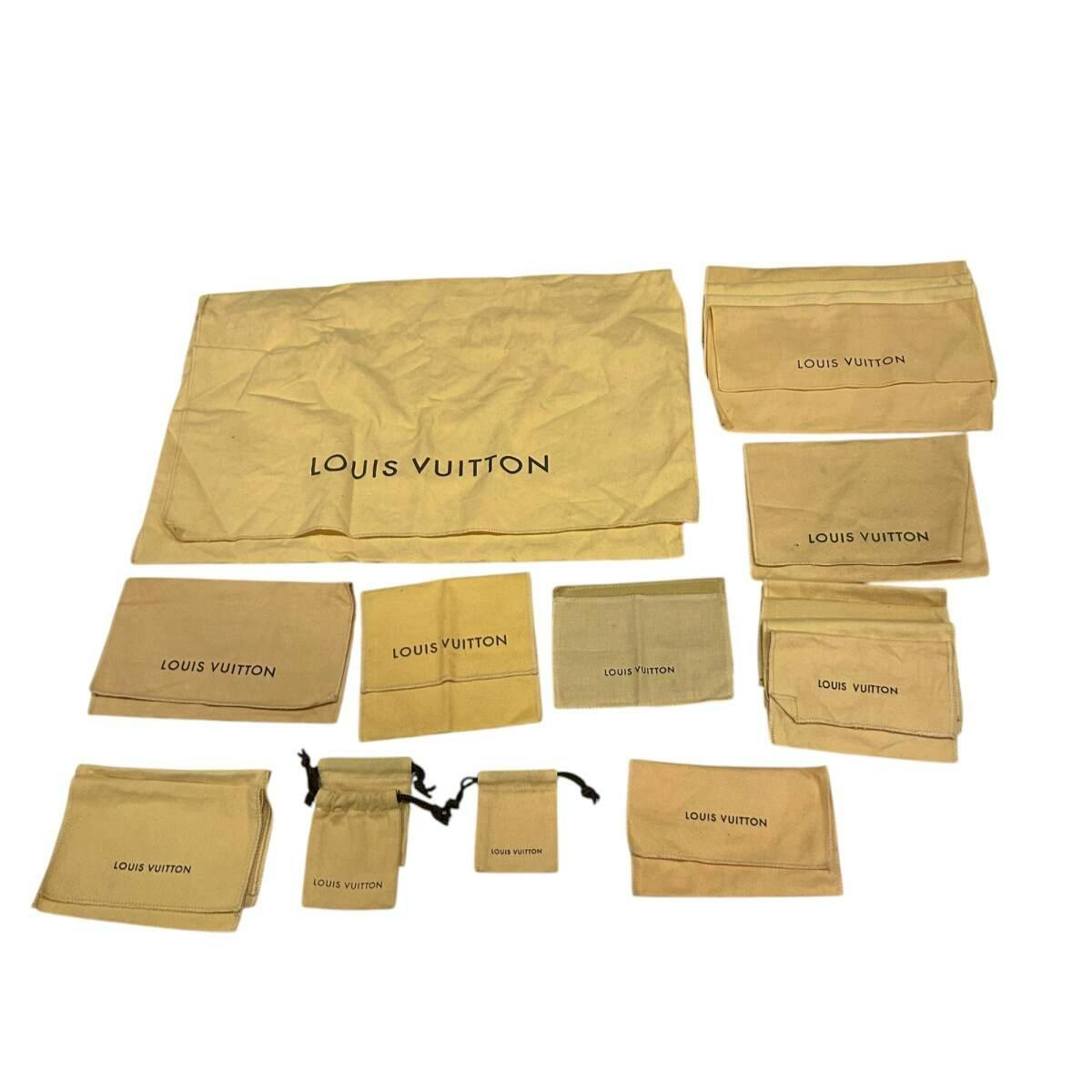 A collection of beige Louis Vuitton cotton dust bags and pouches arranged flat on a white background.