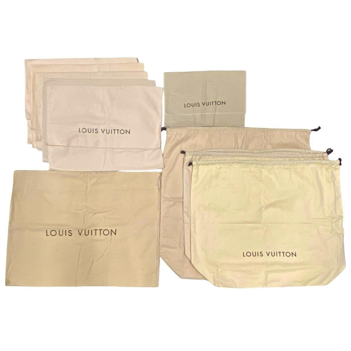 Multiple beige Louis Vuitton dust bags and storage pouches laid flat, several showing the "LOUIS VUITTON" logo.