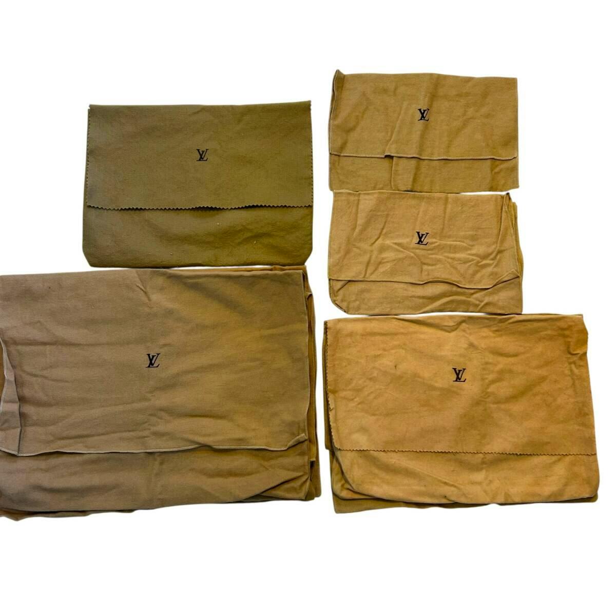 Several beige Louis Vuitton cotton dust bags laid flat showing the LV logo on each.