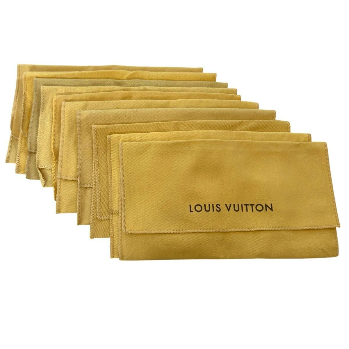 Folded beige Louis Vuitton cotton storage dust bags arranged in a row with LOUIS VUITTON printed on the front.