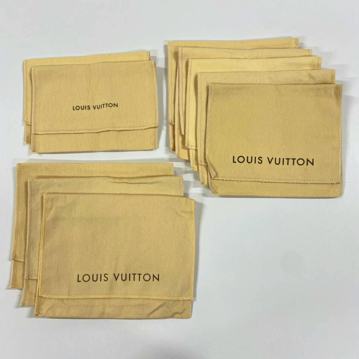 Several beige Louis Vuitton cotton storage/dust bags laid flat on a white surface.