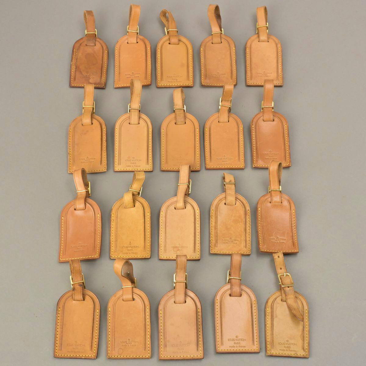 Twenty brown leather Louis Vuitton bag name tags arranged in rows on a neutral background.