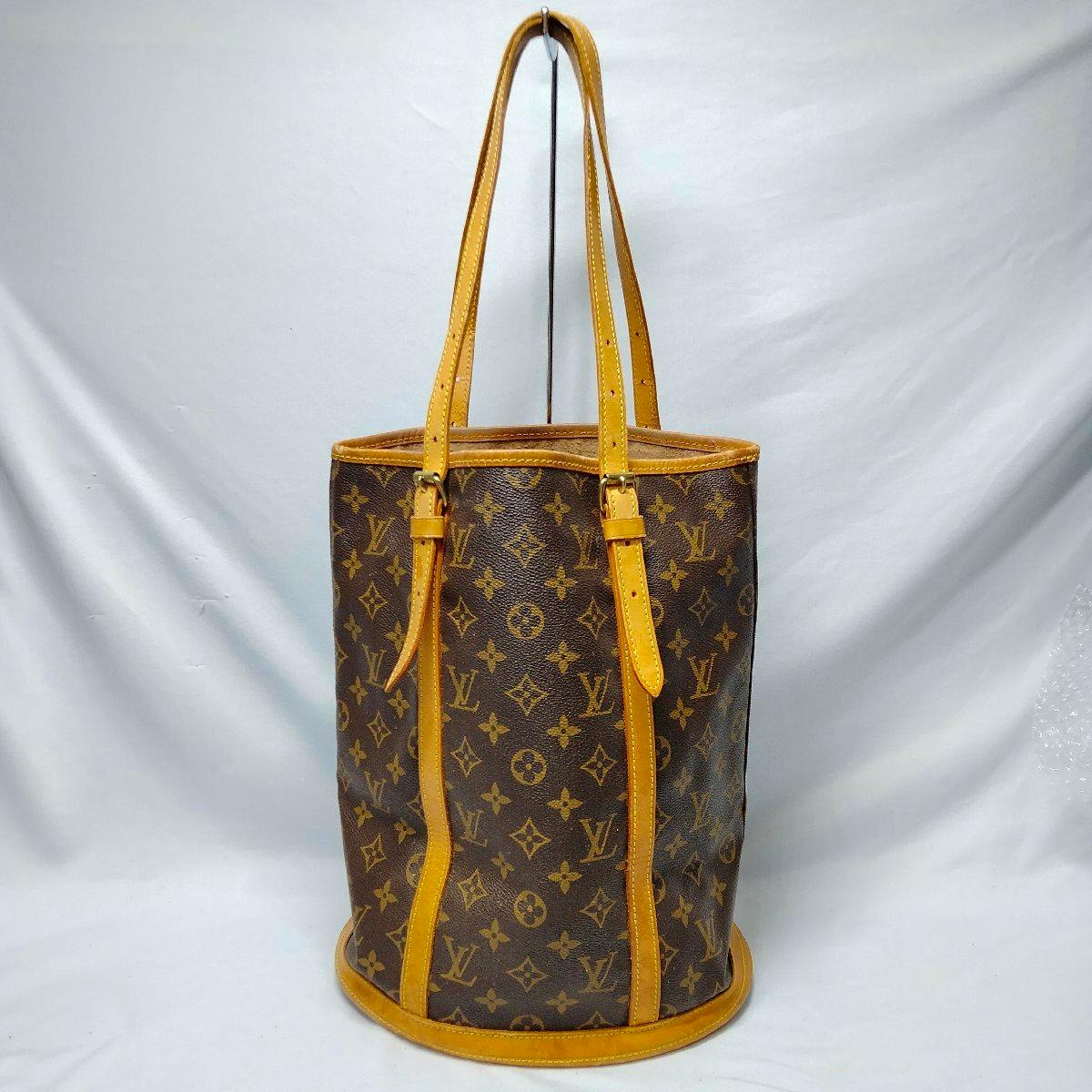 Louis Vuitton Monogram Bucket GM canvas bag with leather trim and long shoulder straps on a white background.