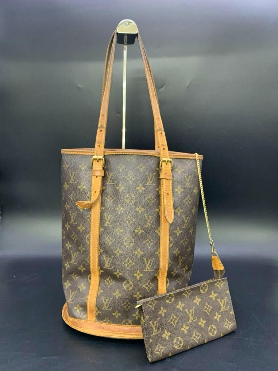 Brown Louis Vuitton monogram canvas Bucket GM shoulder bag with leather trim and attached monogram pouch on a dark background.