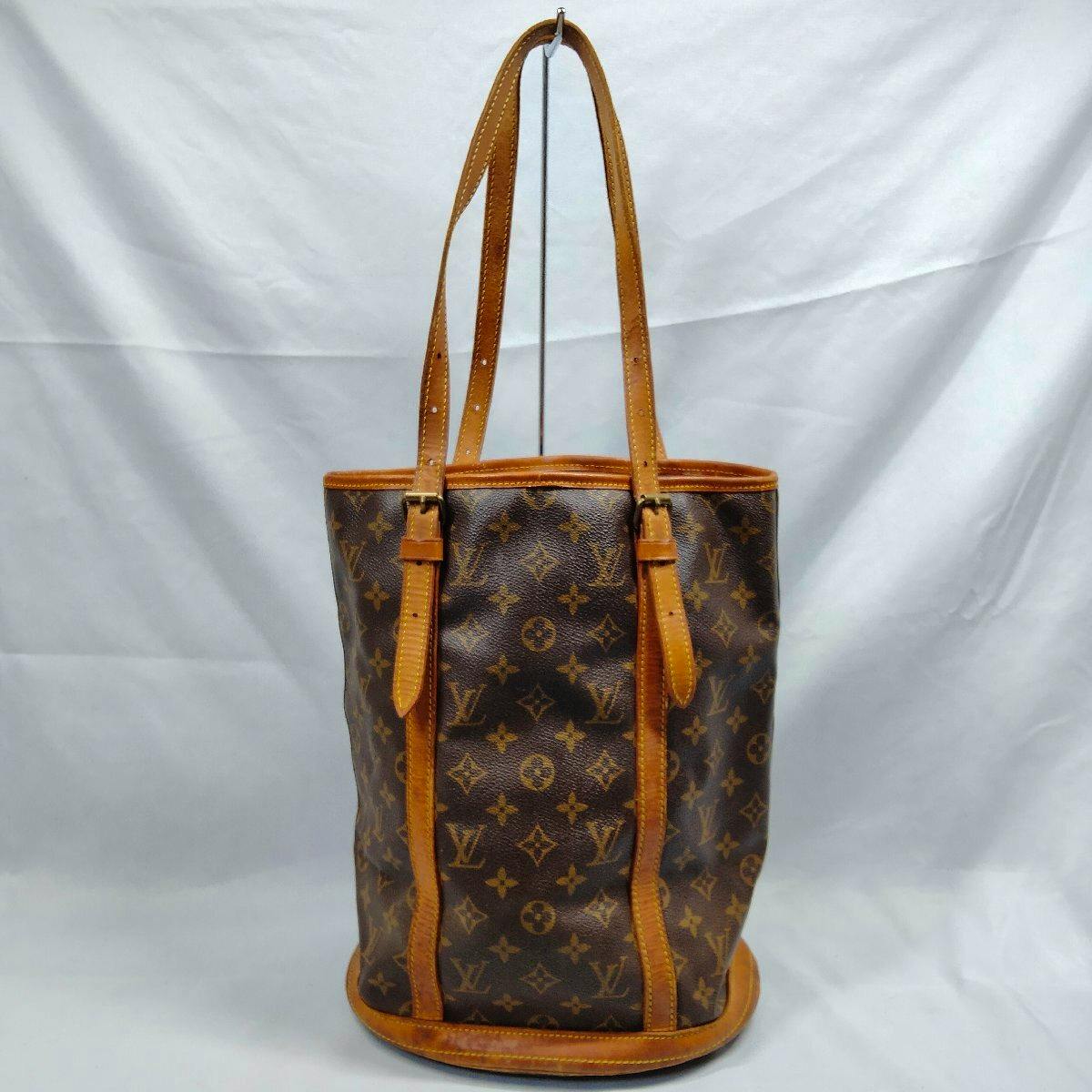 Louis Vuitton Monogram Bucket GM tote bag with cow leather trim and long shoulder straps against a white background.