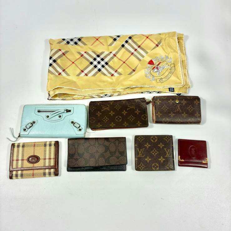 Several wallets and a folded yellow silk scarf laid out on a white background.