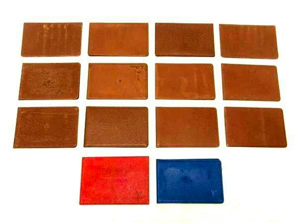 Fourteen Louis Vuitton card/pass cases (mostly brown with one red and one blue) arranged on a white background.