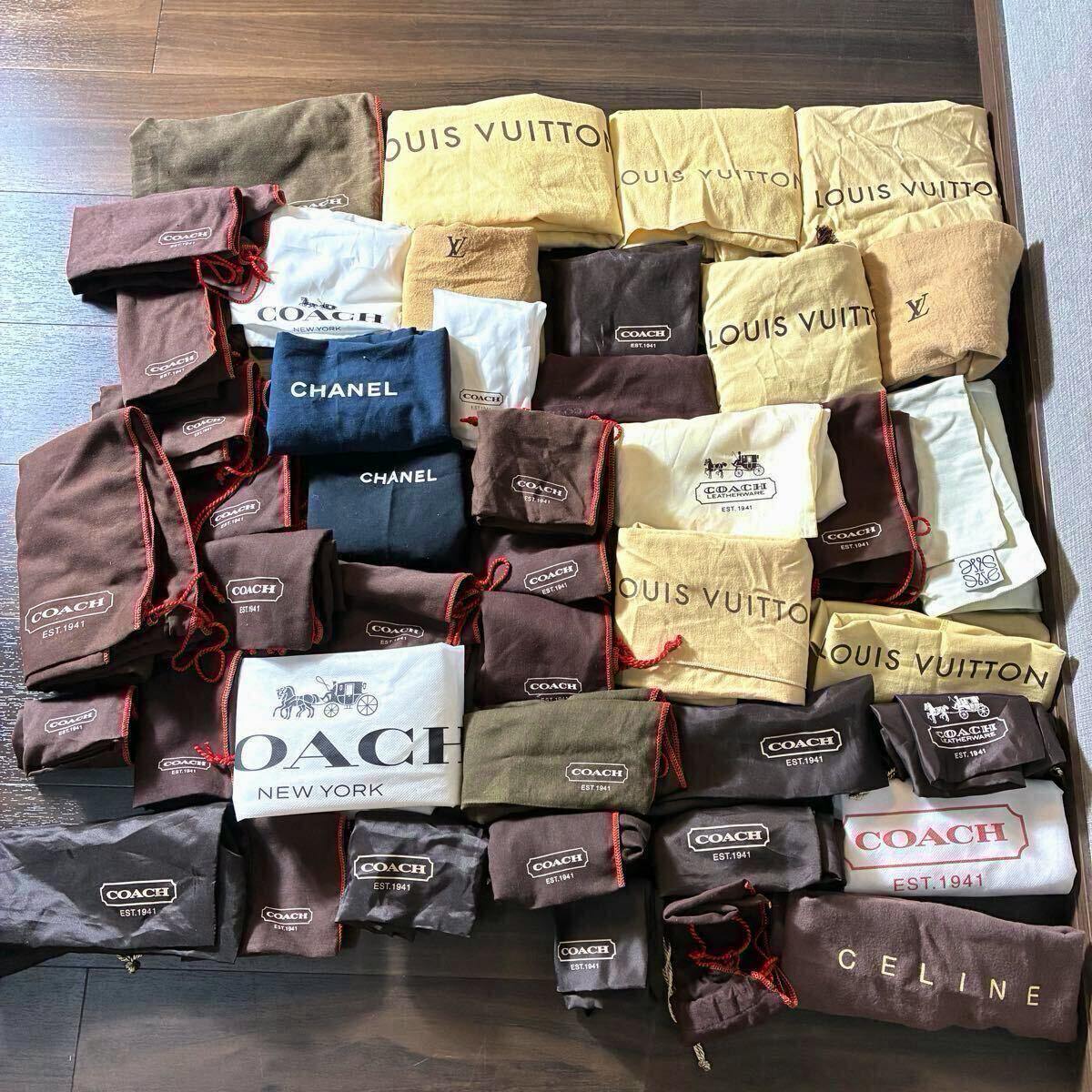 Several folded branded dust bags laid out on a floor, showing logos like COACH, LOUIS VUITTON, CHANEL, and CELINE.