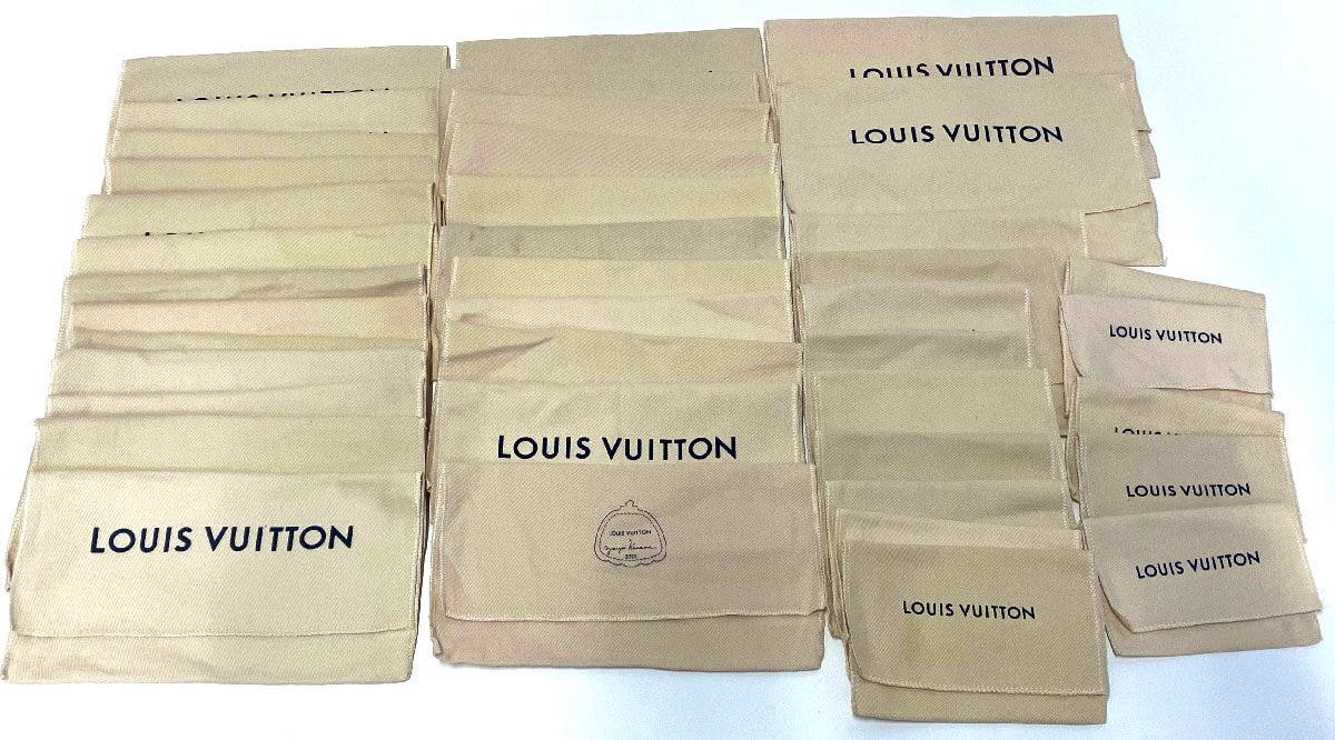 Multiple beige Louis Vuitton cotton dust bags and pouches arranged in rows, several showing the LOUIS VUITTON logo.
