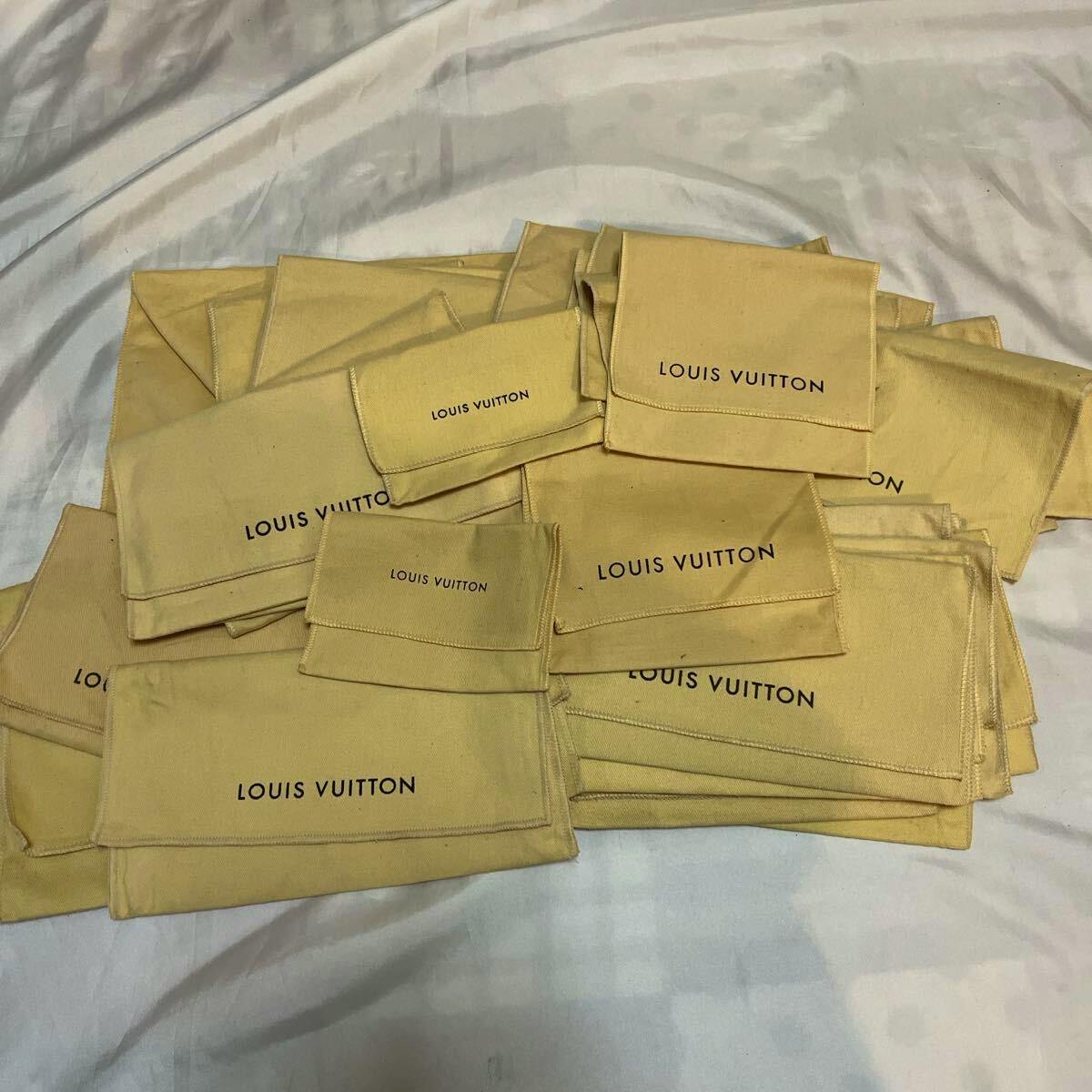 Multiple beige Louis Vuitton cotton dust bags arranged on a surface.