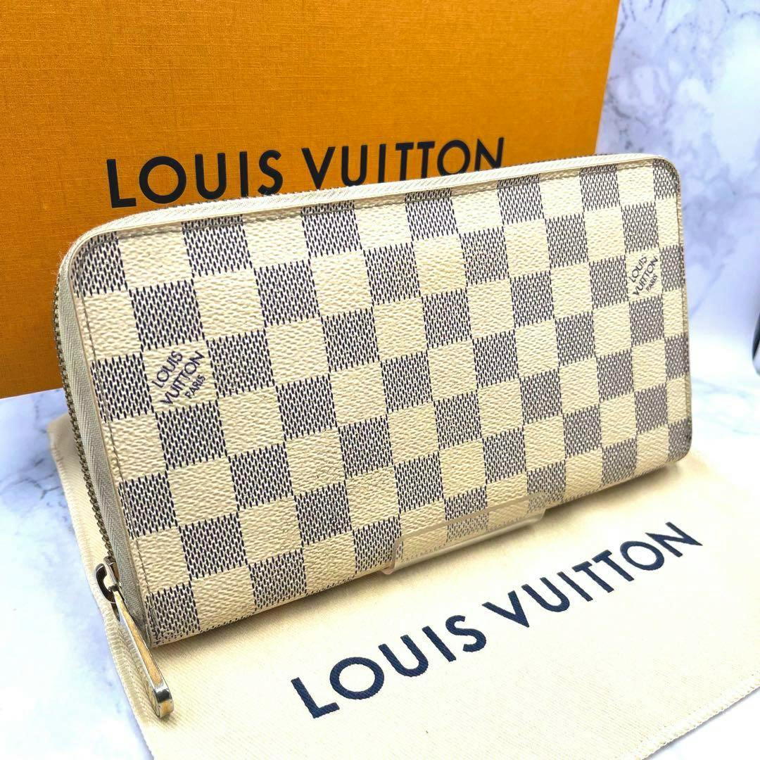 Damier Azur Louis Vuitton Zippy Organizer wallet shown in front of an orange Louis Vuitton box on a Louis Vuitton dust bag.