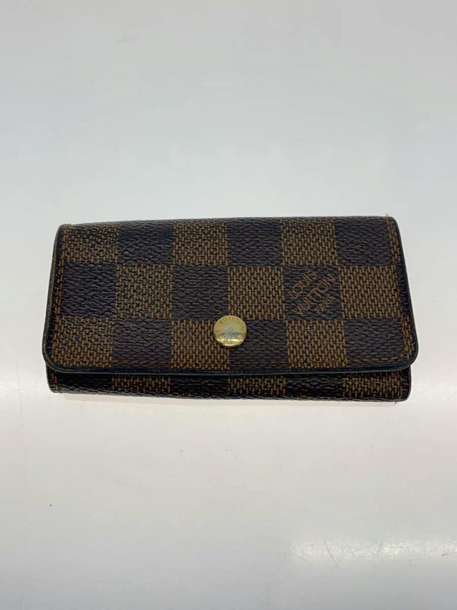 Front view of a brown Damier Ebene Louis Vuitton wallet (cow leather) with a gold snap button placed flat on a white surface.
