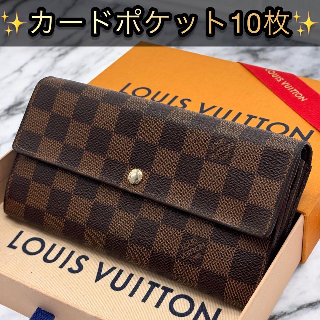Front view of a Louis Vuitton Damier Ebene long wallet (Portefeuille Sarah) resting on a Louis Vuitton box.