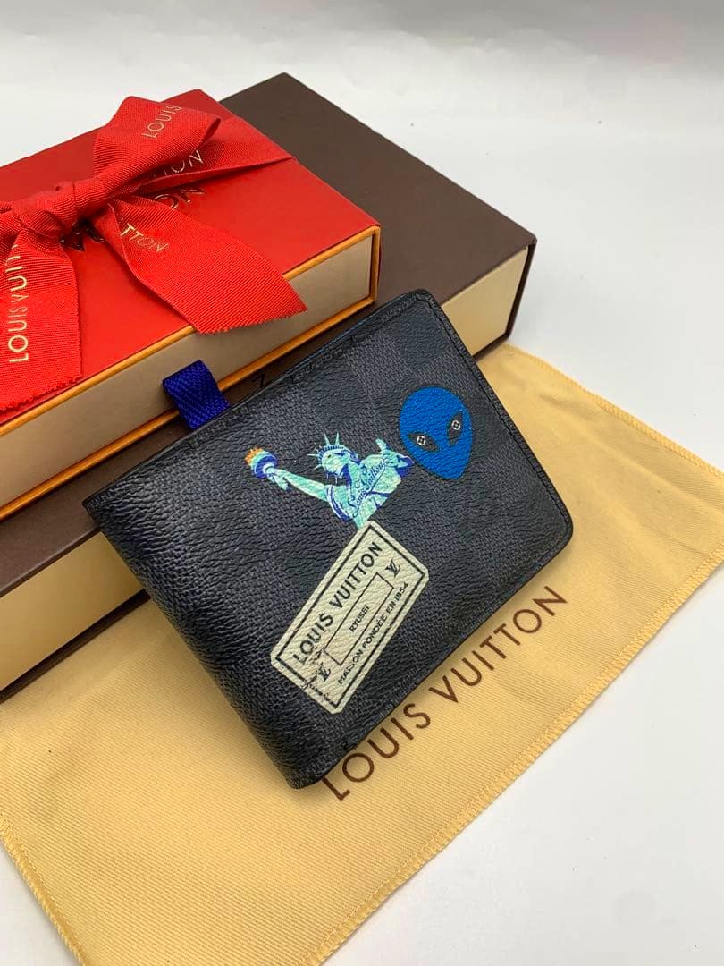 Louis Vuitton Damier Graphite bi-fold wallet with printed graphic motifs displayed on a Louis Vuitton dust bag and boxes.