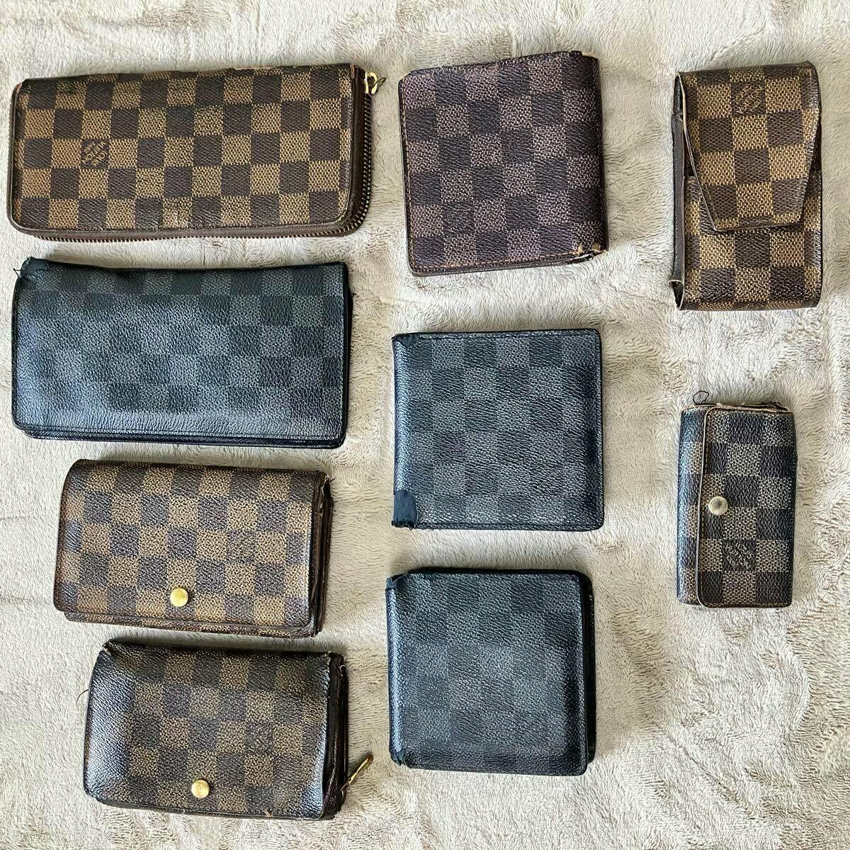 Multiple Louis Vuitton Damier-pattern wallets and small leather cases arranged on a beige fabric surface.