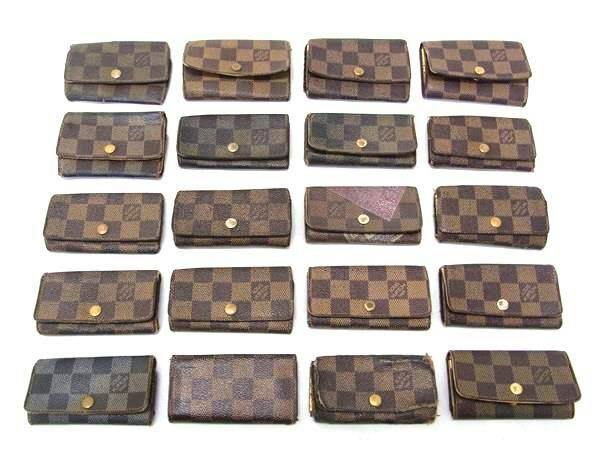 Twenty Louis Vuitton Damier-pattern key cases and small wallets arranged in rows on a white background.