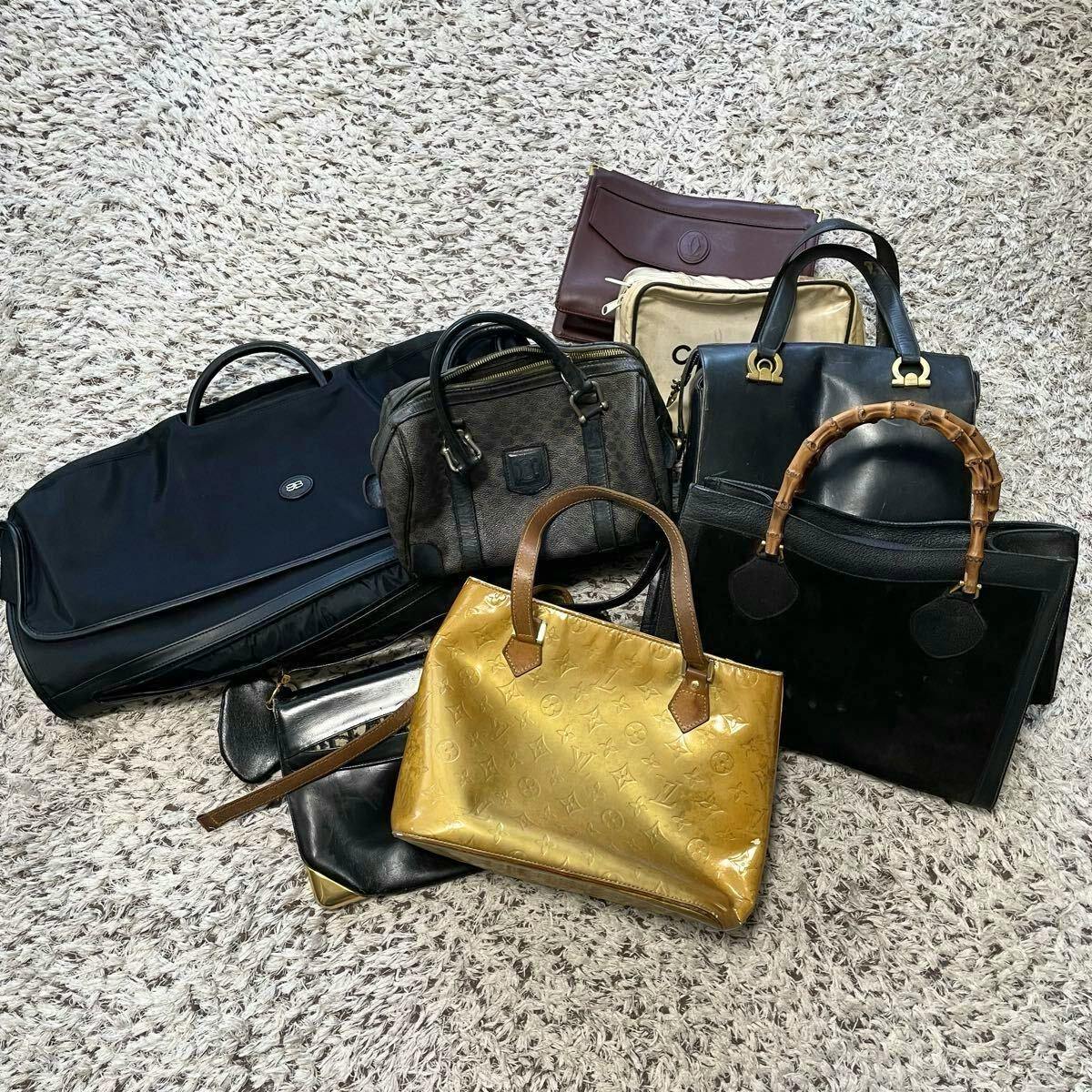 A group of eight leather handbags of various brands arranged on a carpeted floor.