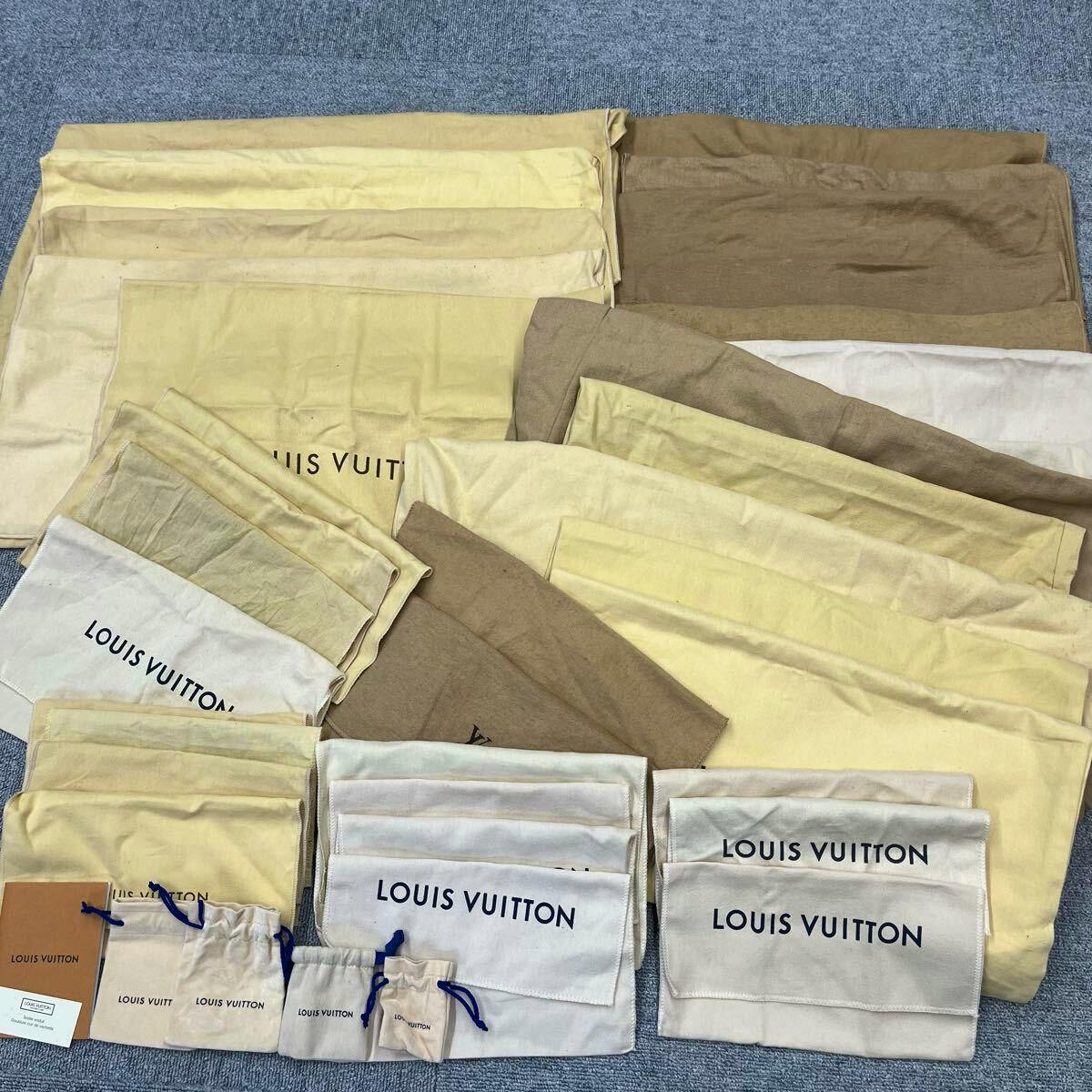 Multiple Louis Vuitton dust bags and small drawstring pouches arranged flat on a floor.