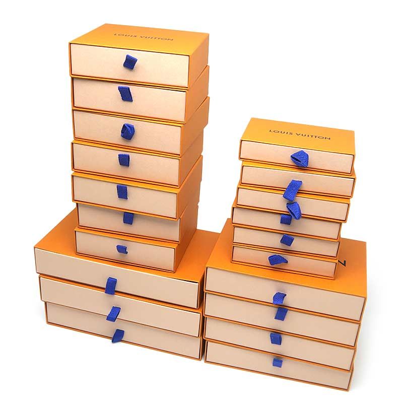 Stack of orange Louis Vuitton gift boxes with blue ribbon pulls arranged in towers.