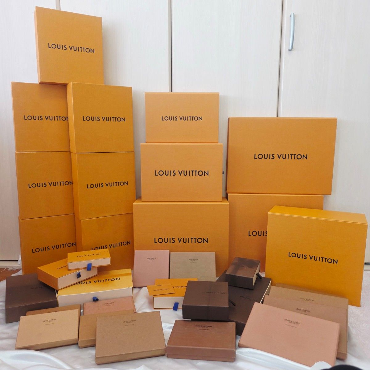 A collection of Louis Vuitton orange paper storage boxes of various sizes stacked and arranged.