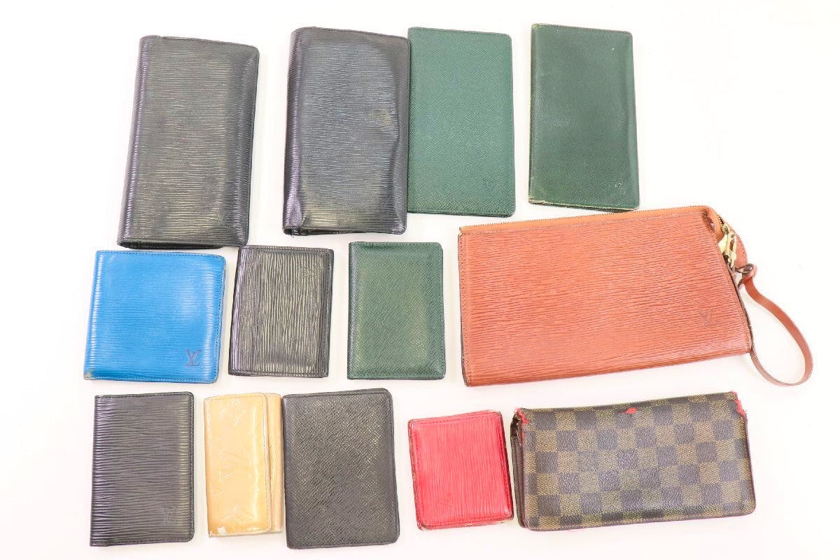 Thirteen Louis Vuitton small goods (wallets, card cases, key cases, and a pouch) arranged on a white background.