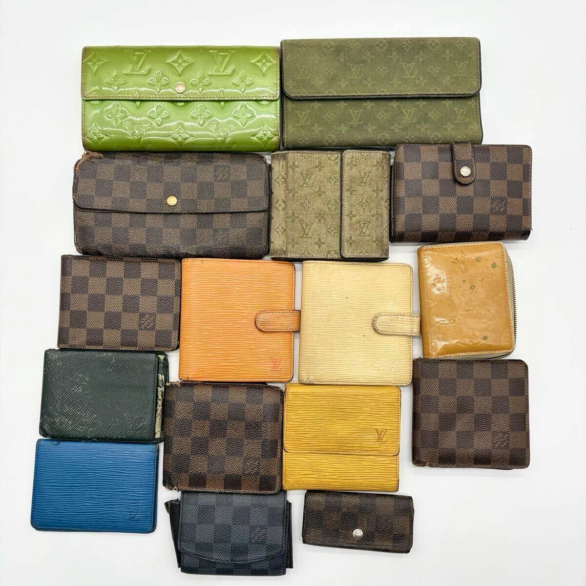 Seventeen Louis Vuitton wallets and small leather goods in assorted colors and patterns arranged on a white background.
