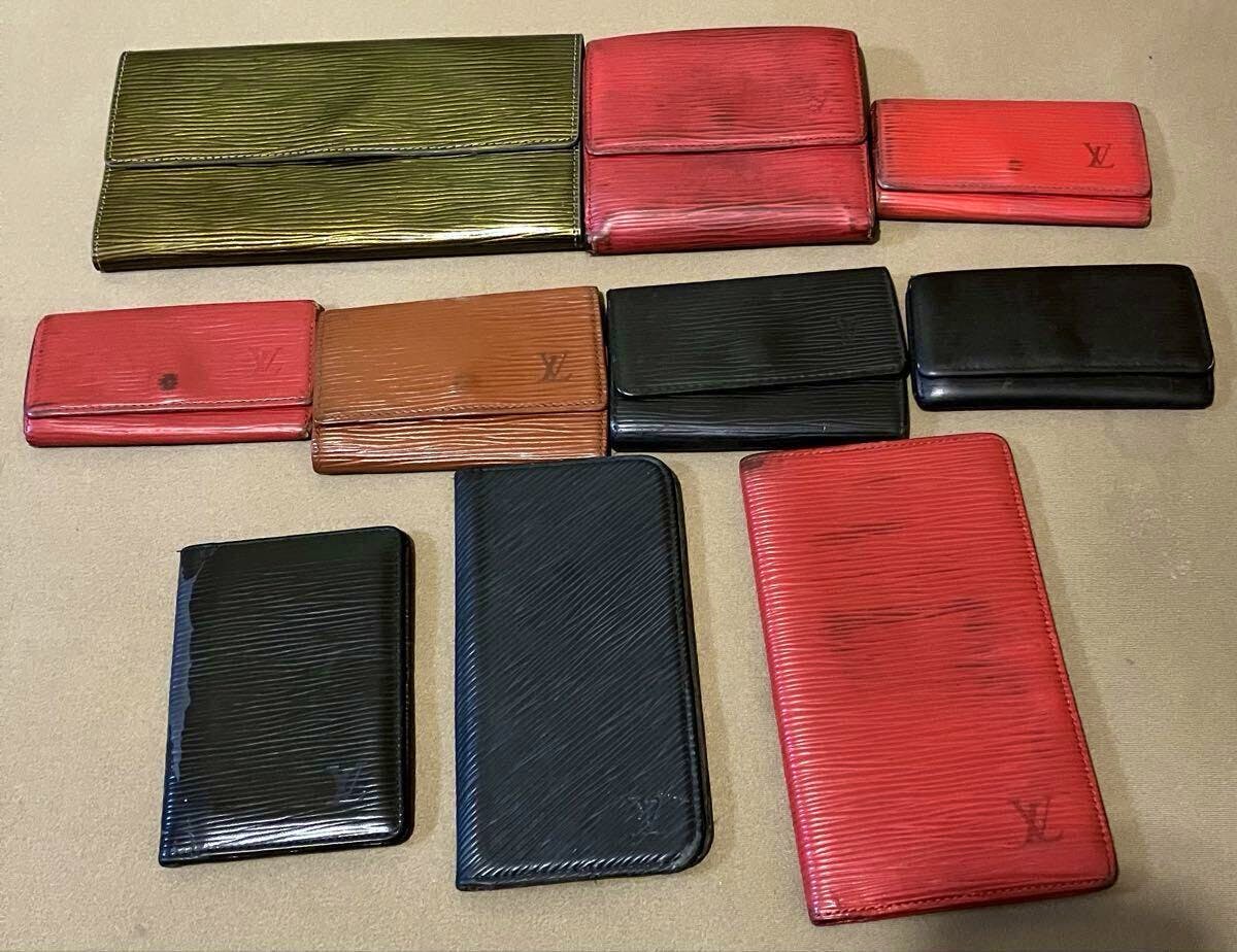 Multiple Louis Vuitton Epi-style wallets and small leather goods arranged on a flat surface, showing various colors and visible wear.