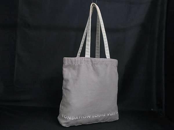 Greige canvas Louis Vuitton Fondation tote bag with shoulder straps displayed against a black background.