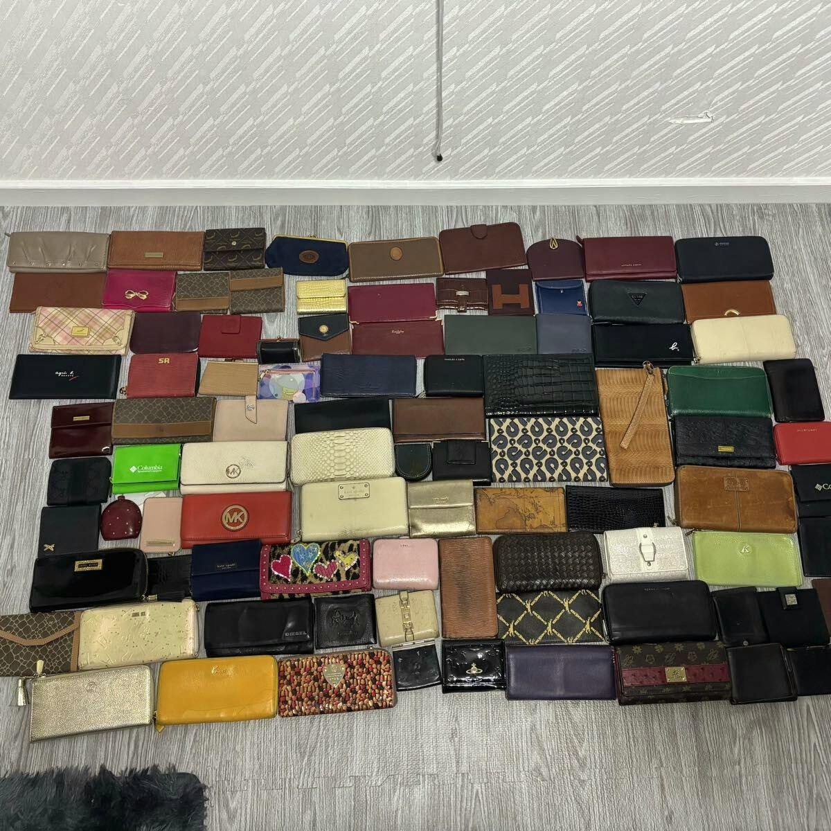 A large assortment of wallets and small leather cases arranged in rows on a floor, photographed from above.