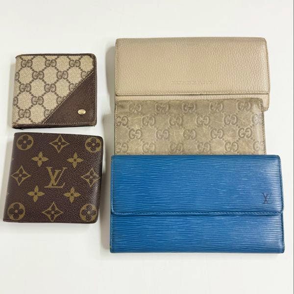 Six wallets arranged on a white background, showing monogram and textured leather styles.