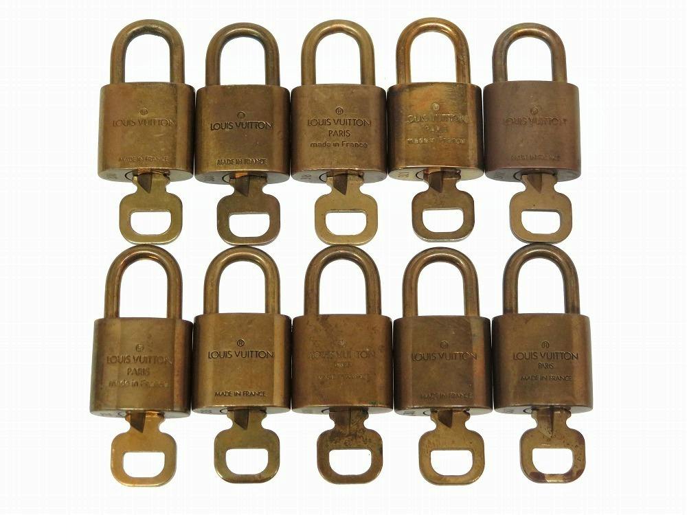 Ten gold Louis Vuitton padlocks with attached keys arranged in two rows on a white background.