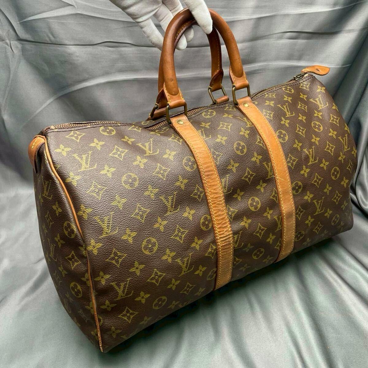 Louis Vuitton Keypol45 monogram Boston travel bag with leather handles and straps shown on a gray fabric background.