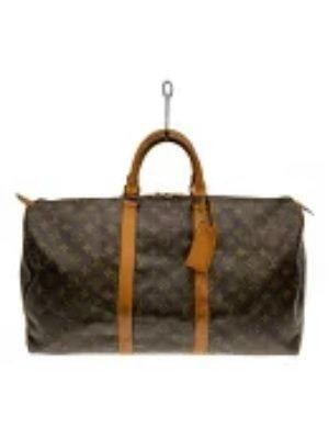 Front view of the Louis Vuitton monogram Keepall 50 duffle bag hanging from a hook, showing handles and leather trim.