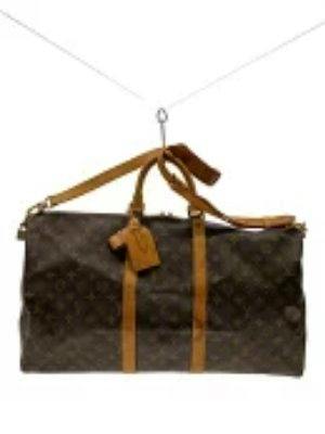 Front view of the Louis Vuitton monogram canvas Keepall duffle bag with brown leather trim and luggage tag.