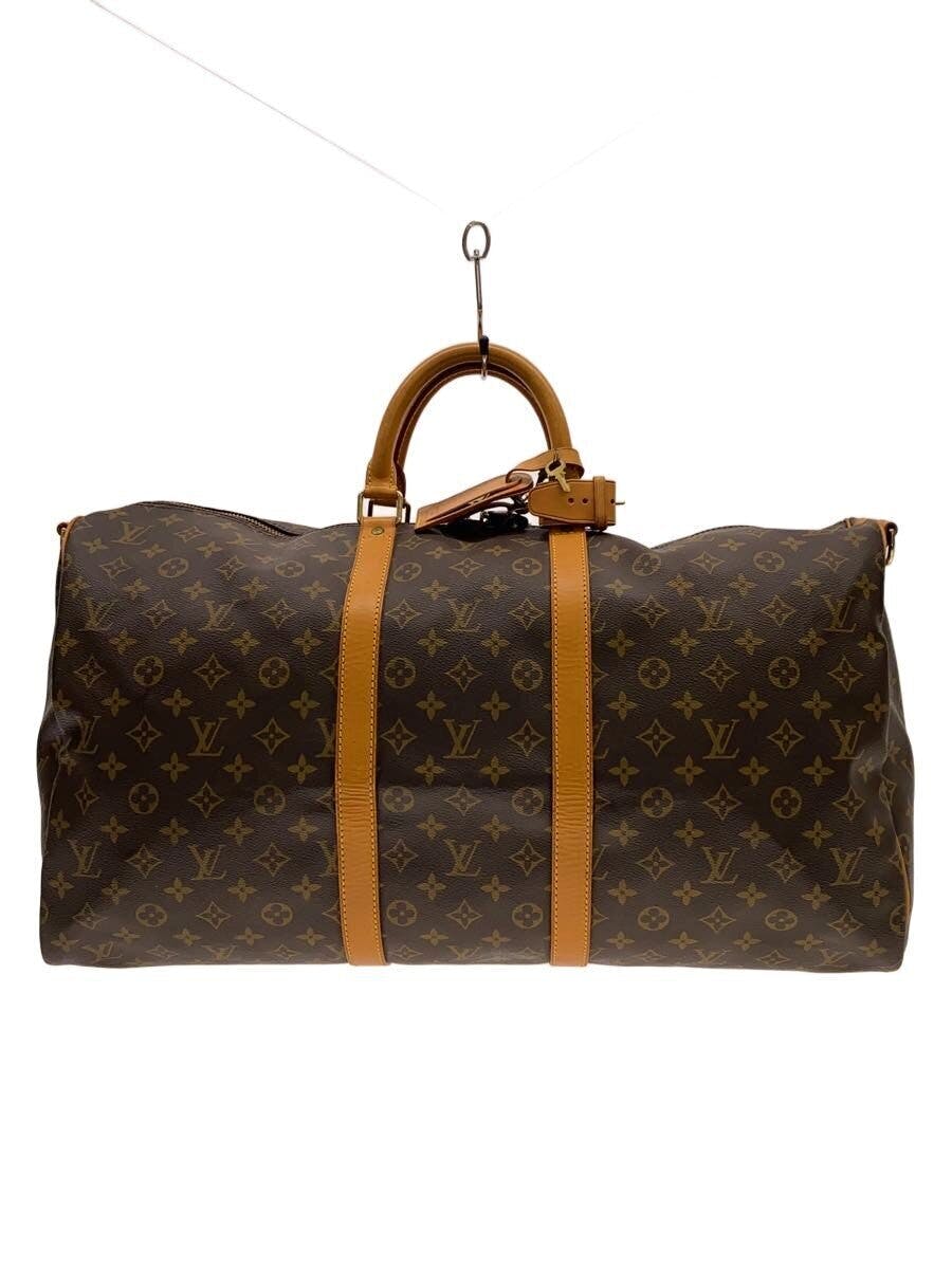 Front view of a Louis Vuitton monogram canvas Keepall Bandouliere 55 bag with brown cow leather handles and straps on a white background.