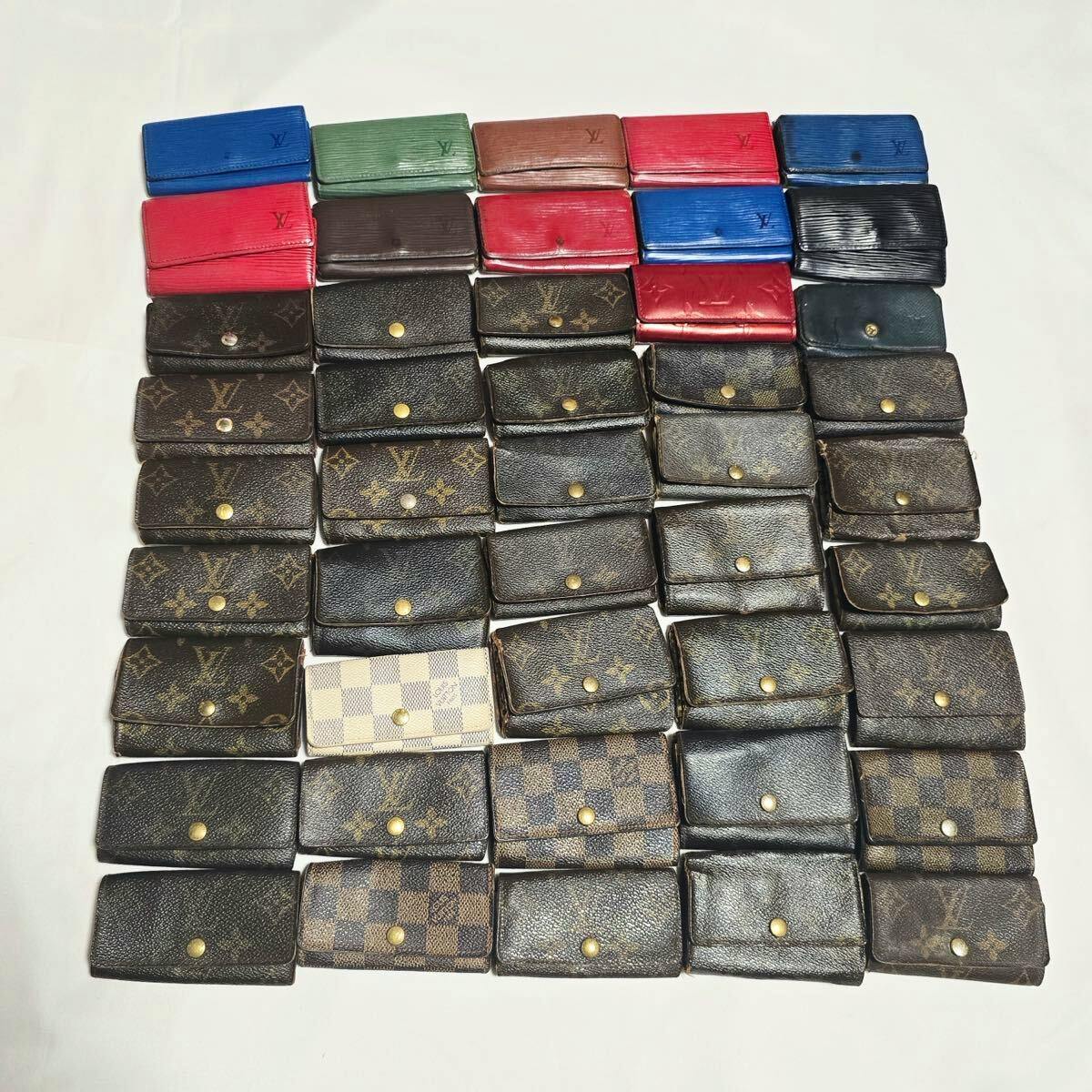 Many Louis Vuitton small wallets and key cases in various patterns and colors arranged on a white surface.
