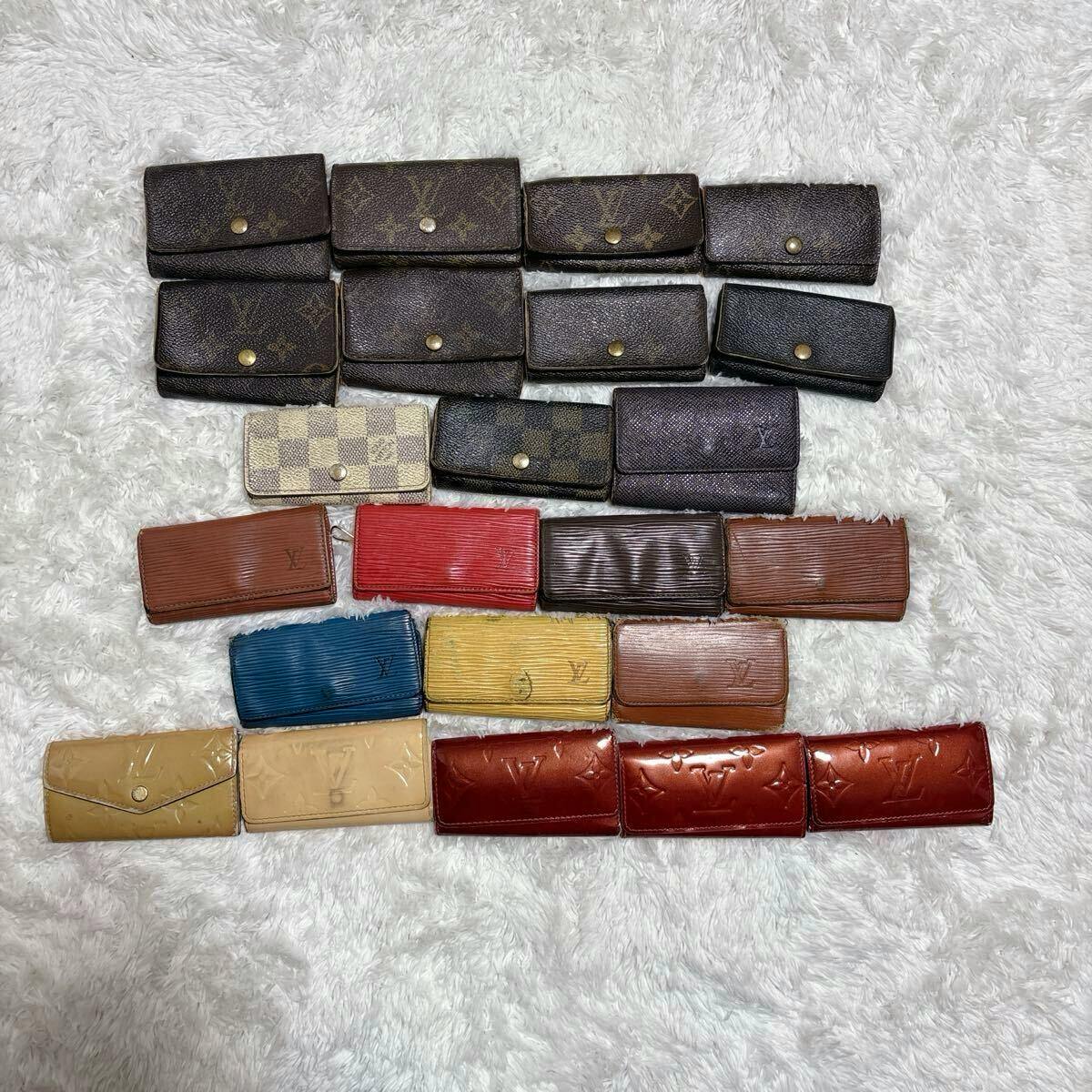Assorted LOUIS VUITTON key cases and small wallets in various patterns and colors arranged on a white fur background.