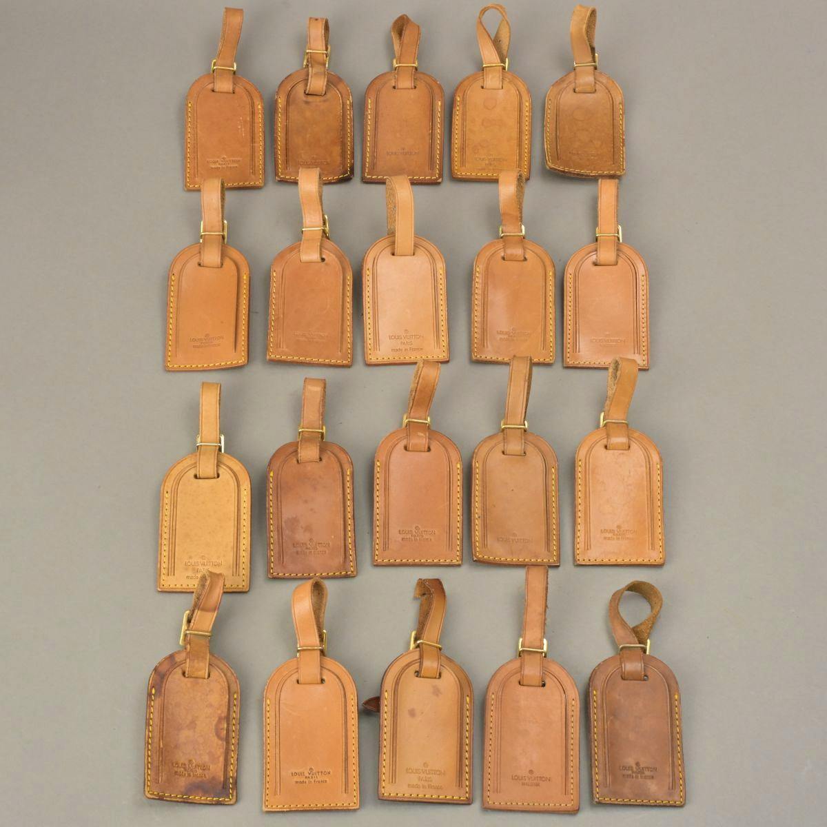 Twenty brown Louis Vuitton leather bag name tags (charms) arranged in rows on a neutral background.