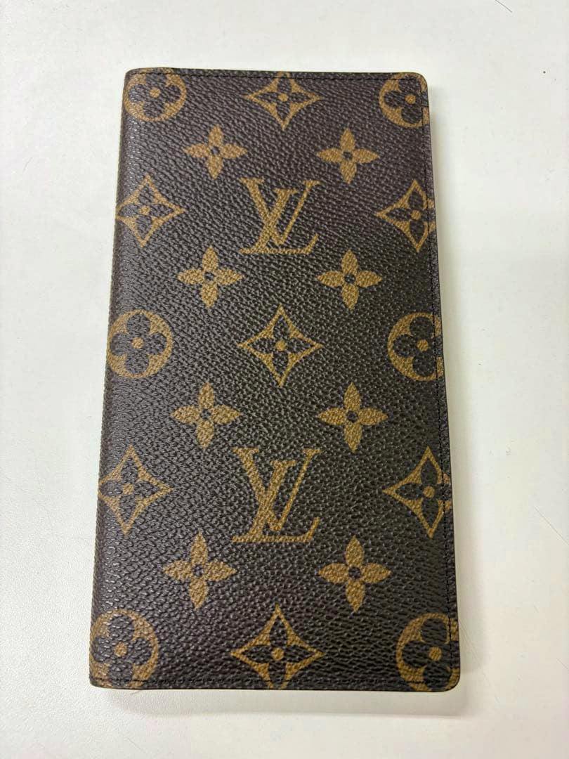 Top-down front view of a Louis Vuitton monogram canvas long wallet on a light surface.