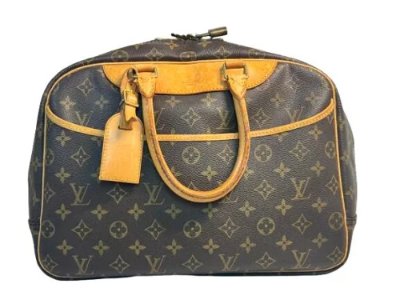 Brown Louis Vuitton monogram canvas mini Boston travel bag with leather handles and a luggage tag on a white background.