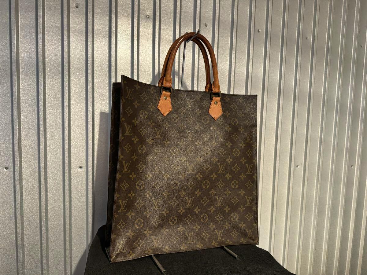 Louis Vuitton monogram canvas Sac Plat tote bag standing upright showing the front and leather handles.