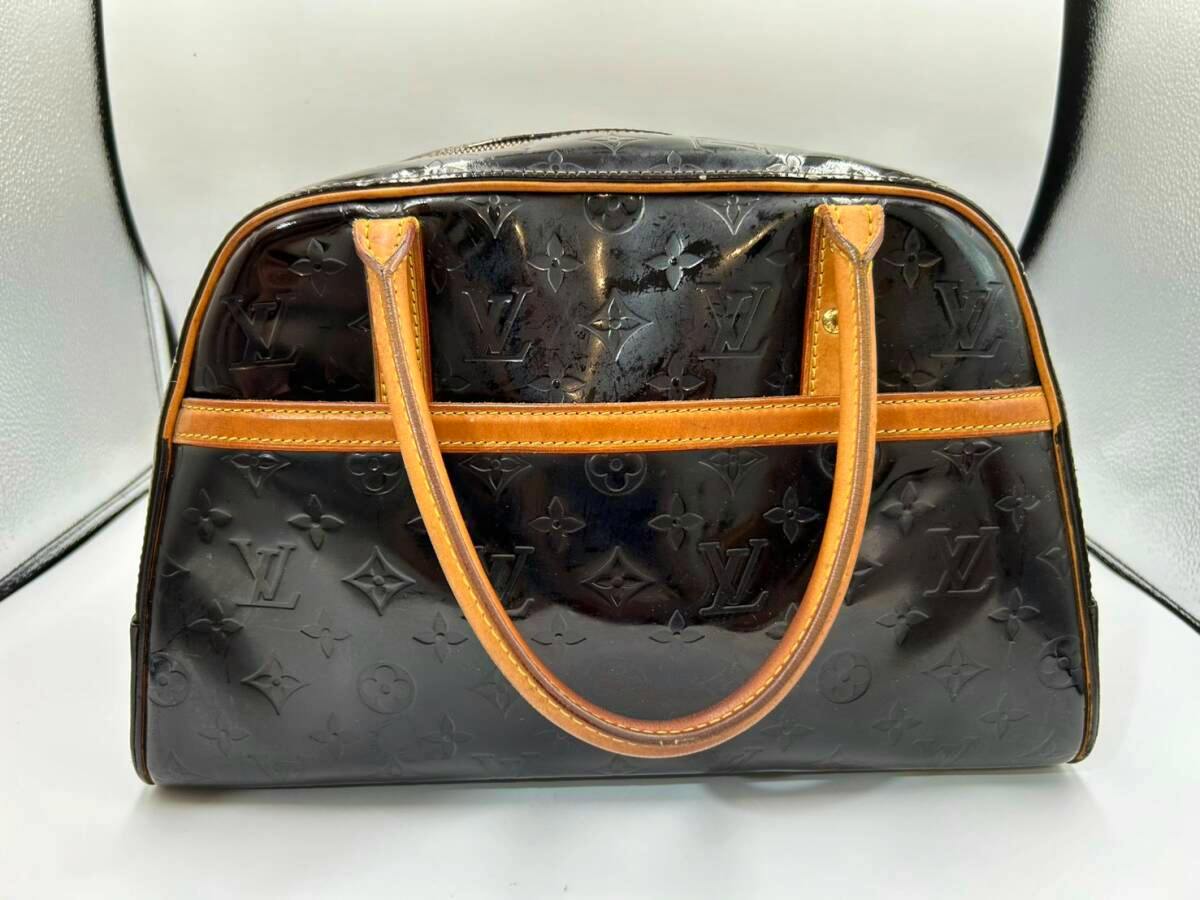 Front view of a black Louis Vuitton Monogram Vernis Tompkins handbag with brown leather handles and trim.
