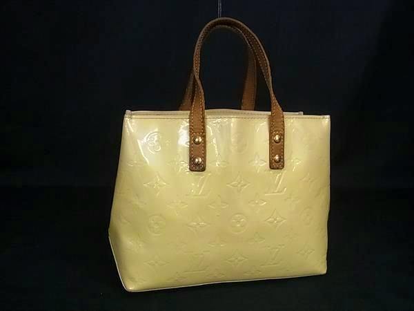 Yellow Louis Vuitton Monogram Vernis tote bag with brown leather handles displayed against a dark background.