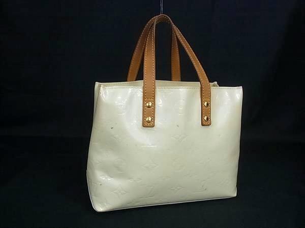 Front view of the Louis Vuitton Monogram Vernis M91336 pearl-cream tote handbag with tan leather handles on a black background.