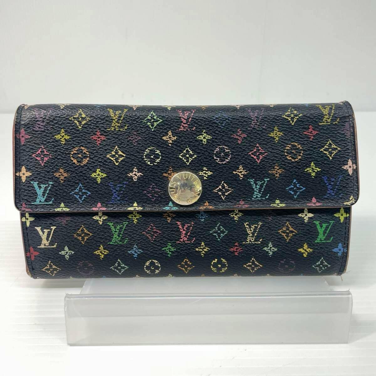 Front view of the Louis Vuitton Monogram Multicolor long wallet (M93533) on a clear stand, showing black canvas with multicolor monogram and a round gold-tone snap.
