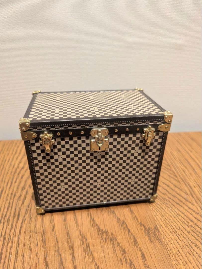 Front view of the Louis Vuitton MINI MALLE CHAPEAUX small trunk showing a checkerboard exterior and gold-tone hardware on a wooden surface.
