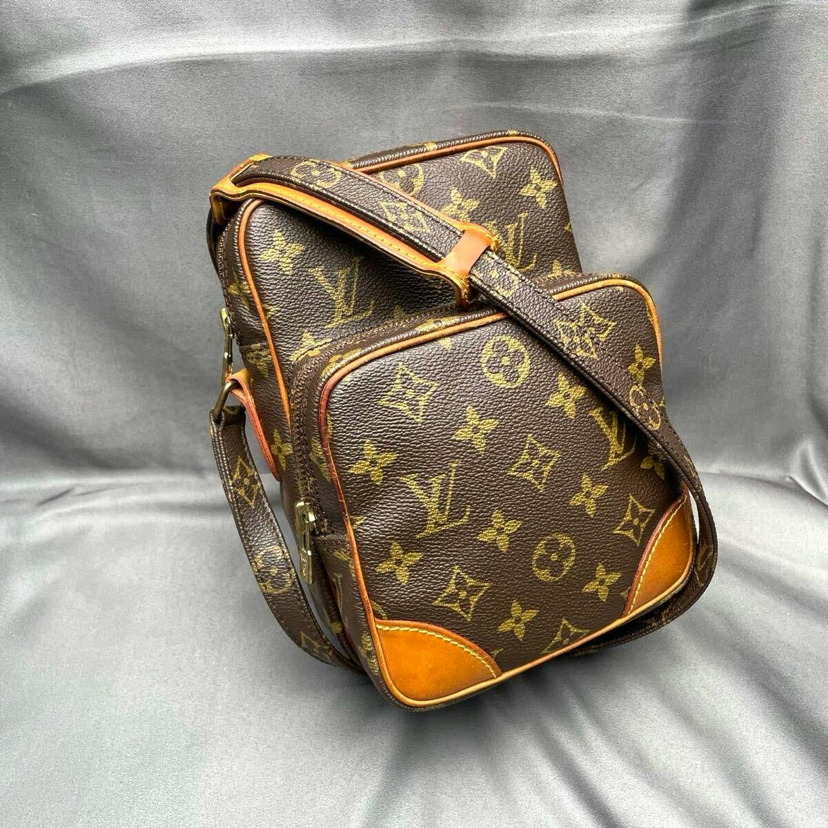 Louis Vuitton monogram Amazon shoulder bag in brown canvas with leather trim and adjustable strap on a gray background.