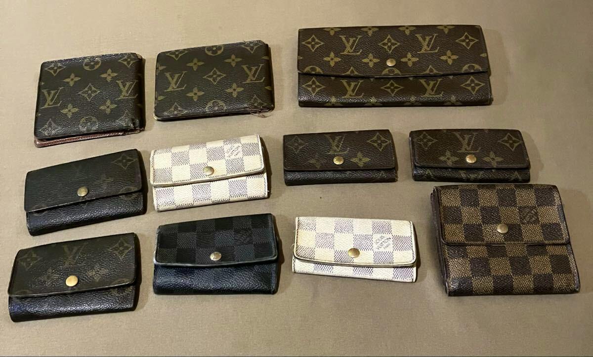 Eleven Louis Vuitton small wallets and key cases in Monogram and Damier patterns arranged on a flat surface.