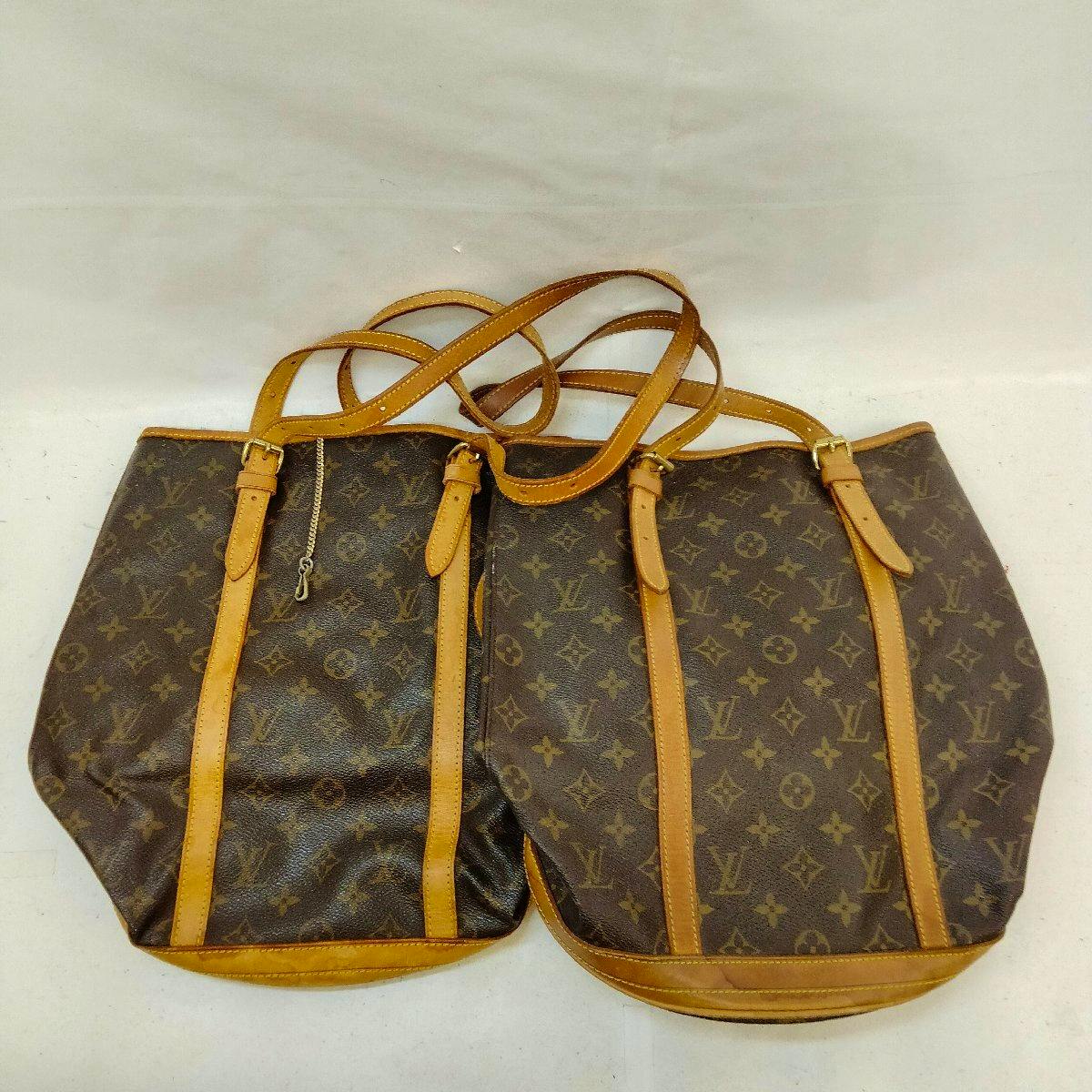 Two Louis Vuitton monogram canvas bucket bags with tan leather straps and trim shown side by side on a plain background.