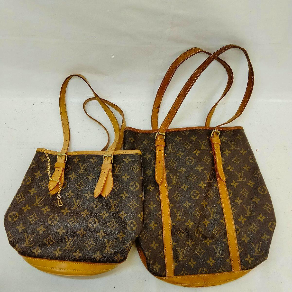 Two Louis Vuitton monogram canvas bucket bags with leather trim and shoulder straps shown on a white background.